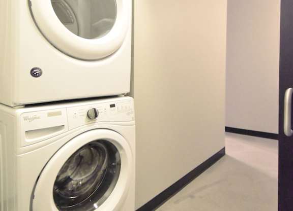 Two white front loading washing machines stacked on top of each other.