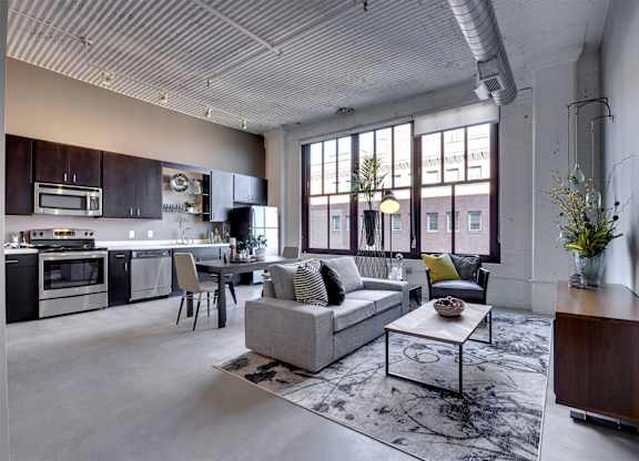 A modern open plan living and kitchen area with a grey sofa and a coffee table.