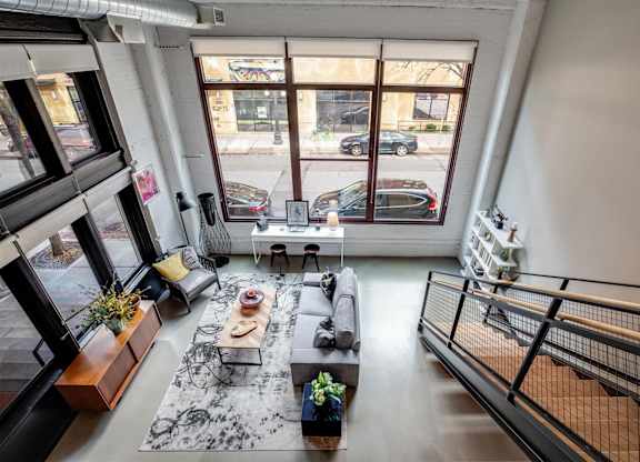 A living room with a black and white rug, a wooden coffee table, and a staircase.