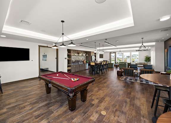 A room with a pool table and a bar area.