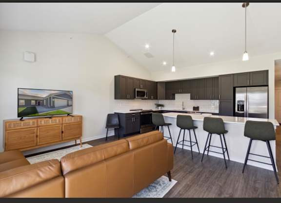 A modern living room with a brown leather couch and a television on a wooden cabinet.
