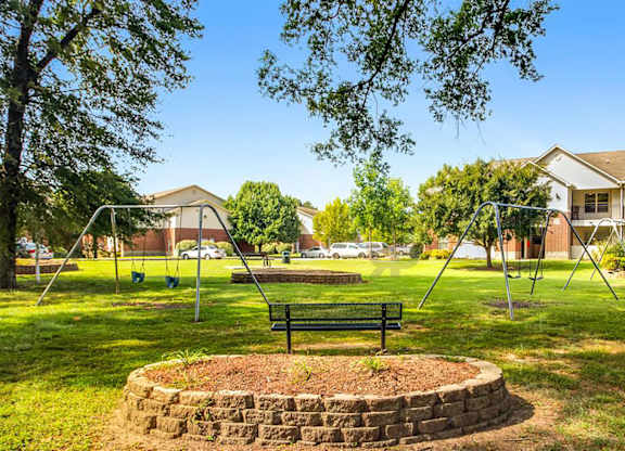 A park with a swing set and a bench.