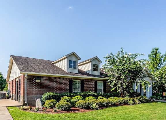 A house with a well-maintained lawn and a clear blue sky above.