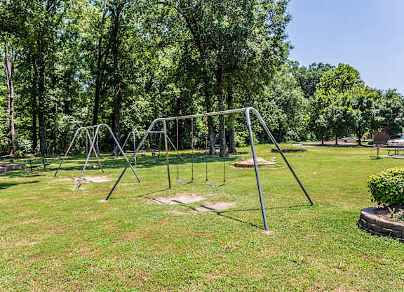 A playground with swings and a slide in a grassy area.
