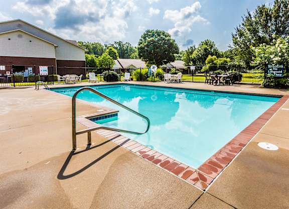 A large outdoor swimming pool with a red brick border.