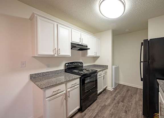 A kitchen with black appliances and white cabinets.