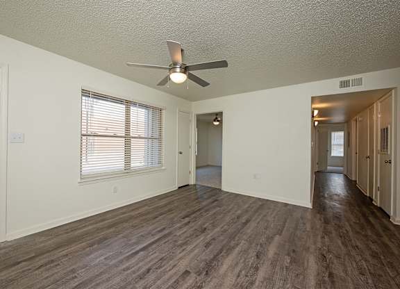 A room with a ceiling fan and wooden flooring.