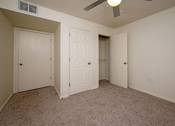 A room with carpeted floor and three doors.