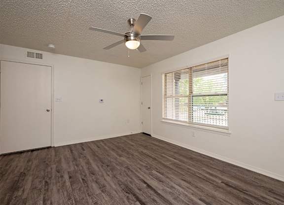 A room with a ceiling fan and wooden flooring.