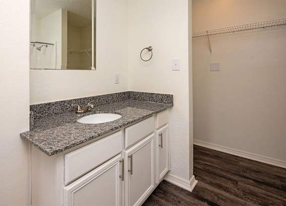 A bathroom with a granite countertop and white cabinets.