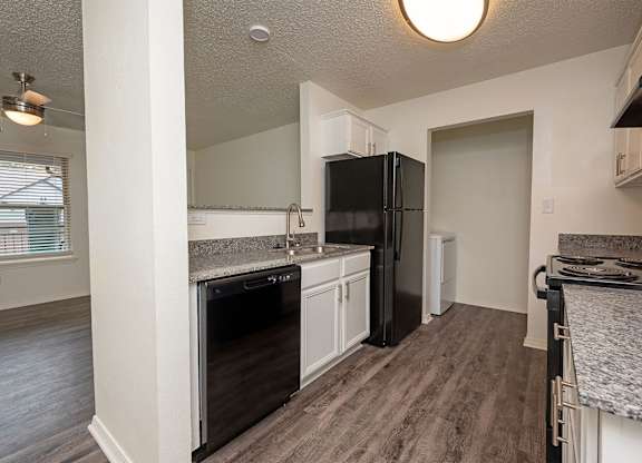A kitchen with a black refrigerator and a marble countertop.