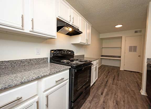 A kitchen with black appliances and white cabinets.