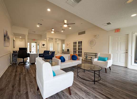 A spacious living room with white furniture and a ceiling fan.
