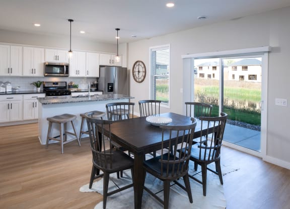 a dining area with a table and chairs and a kitchen in the background