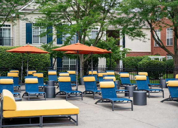 an outdoor lounge area with yellow and blue chairs and orange umbrellas
