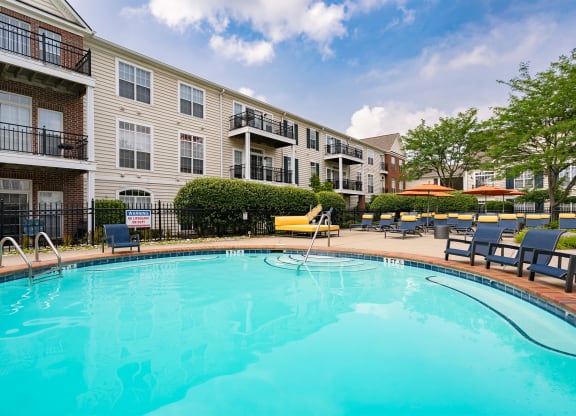 a swimming pool with lounge chairs and umbrellas in front of a building