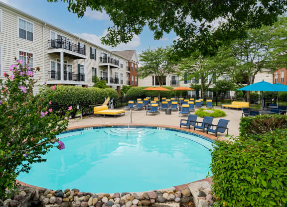 a swimming pool with lounge chairs and umbrellas in front of a building