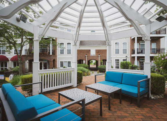 a patio with blue couches and tables in front of an apartment building
