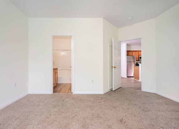 a living room with carpet and a door to a kitchen