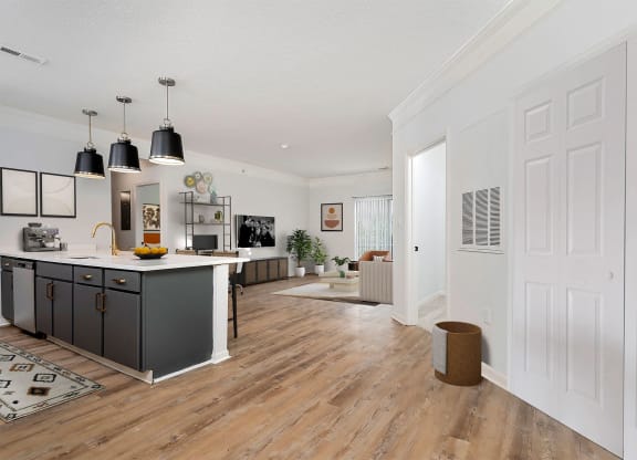 a kitchen and living room with white walls and wooden floors