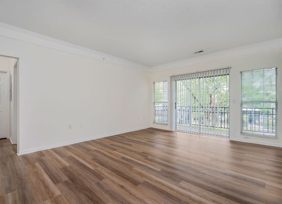 an empty living room with wood flooring and a balcony