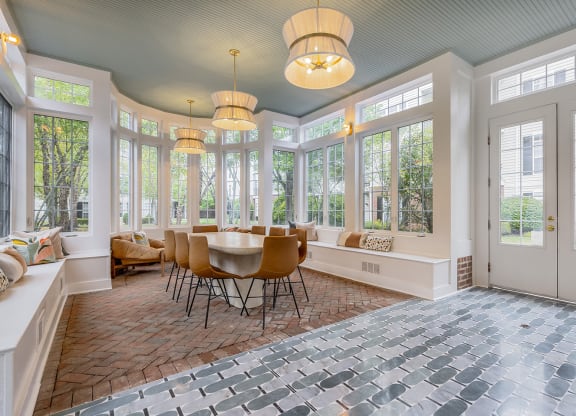 a sun room with a table and chairs and large windows