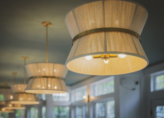 a row of hanging wooden lamps in a room with windows