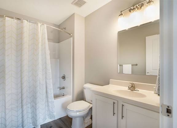 A white bathroom with a toilet, sink, and shower.