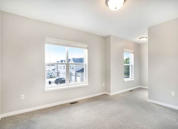 A spacious room with a large window and a view of a residential area.