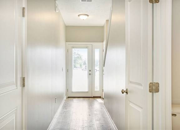 A long hallway with white doors and a light on the ceiling.
