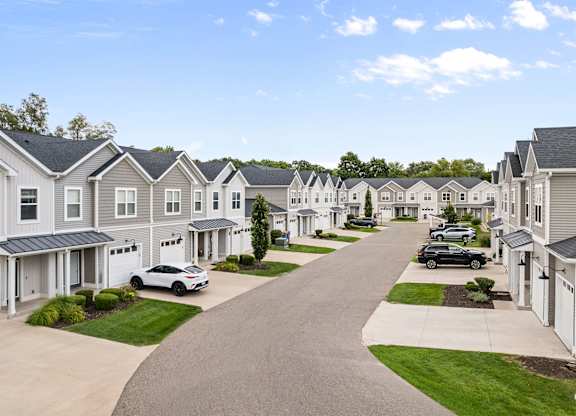 A row of houses with cars parked in front.