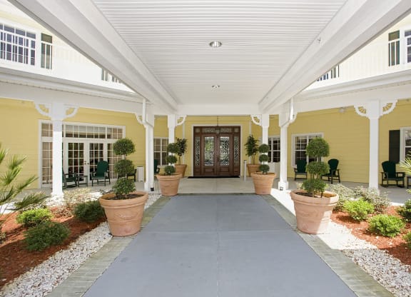 a covered walkway with potted plants leads to a large wooden doorat Arbor Oaks at Lakeland Hills, Lakeland