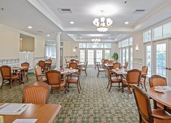 a dining room with tables and chairs and a chandelier at Arbor Oaks at Greenacres, Greenacres