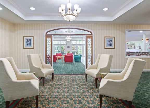 a room with chairs and a chandelier and a table in the backgroundat Arbor Oaks at Greenacres, Greenacres, 33467