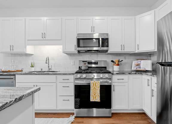 A modern kitchen with white cabinets and stainless steel appliances.