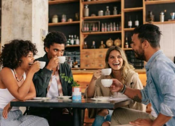 Four people are sitting at a table in a cafe.