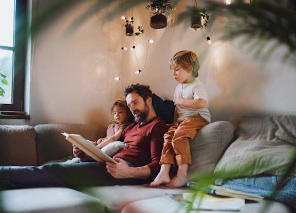 A family of three is sitting on a couch together.