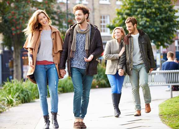 Four people walking together on a sidewalk.