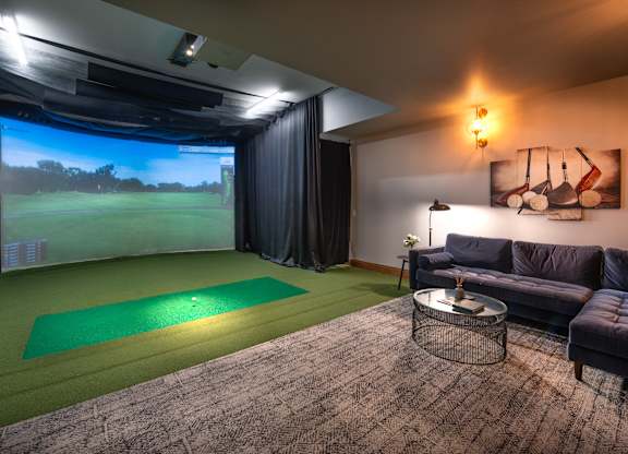 a living room with a golf simulator and a projector screen