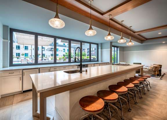 a bar with wooden stools in a room with a row of chairs
