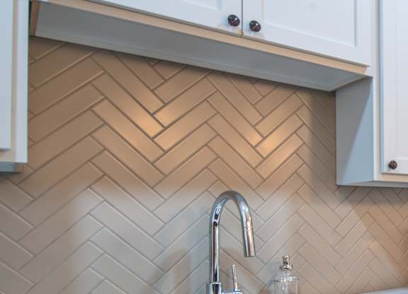 a kitchen with white cabinets and a sink and subway tiles
