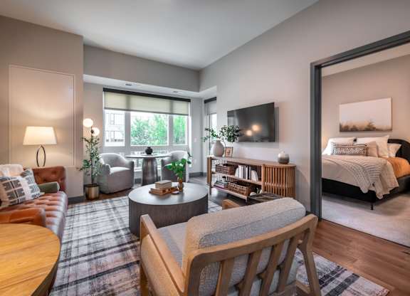 a living room with a bedroom in the background and a table and chairs