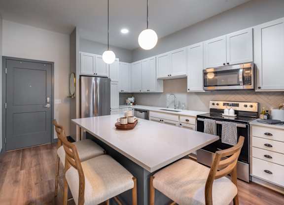 a kitchen with white cabinets and a white table and chairs