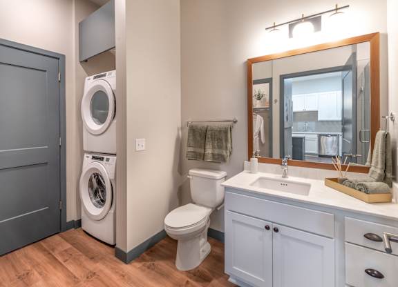 a bathroom with a toilet sink and a washing machine    and a mirror