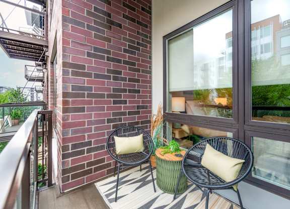 a balcony with two chairs and a table and a brick wall