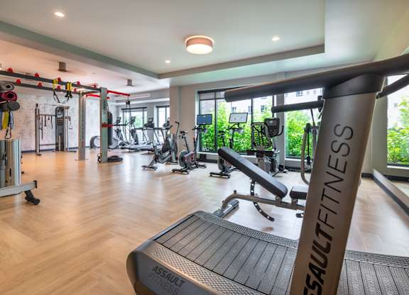 a gym with treadmills and other exercise equipment in a building with windows