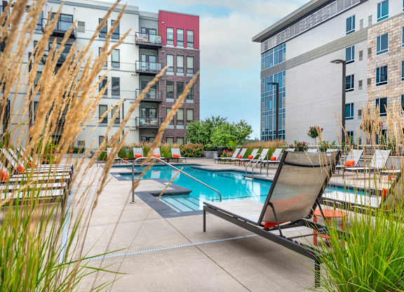 a swimming pool with lounge chairs in front of an apartment building