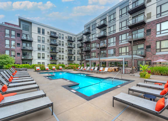 an outdoor pool with lounge chairs and an apartment building