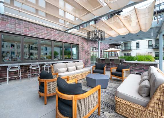 an outdoor patio with wicker furniture and a brick wall