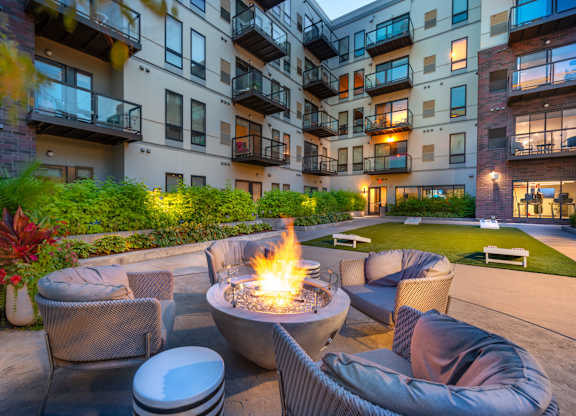 an apartment courtyard with a fire pit and chairs